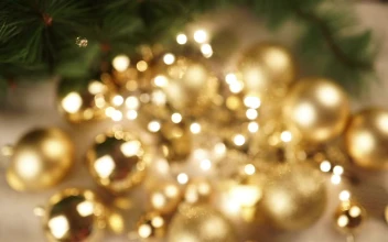 Stock Video Hand Holds Out Christmas Ornament With Gold Bokeh Background For PC