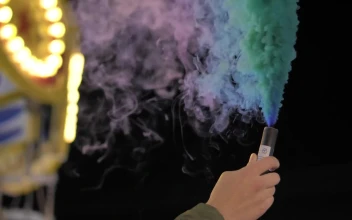 Stock Video Hand Holding A Multicolored Smoke Bomb At The Fair For PC