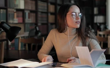 Stock Video Girl Rubs Head In Pain While Studying Late In Library For PC