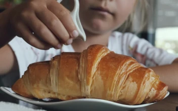Stock Video Girl Adding Sweet Milk On A Croissant For PC