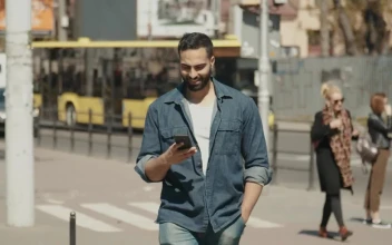 Stock Video Hopeful Man Smiles At Social Media While Walking Through City Animated Wallpaper