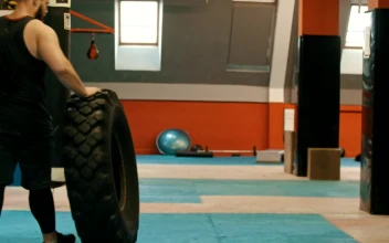 Stock Video Man In A Gym Walking With A Big Truck Wheel Animated Wallpaper