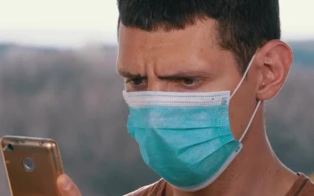 Stock Video Man With A Face Mask Looking At Smart Phon Animated Wallpaper