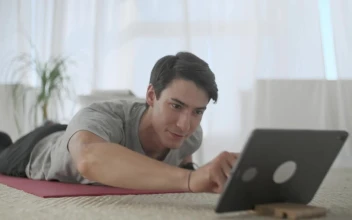 Stock Video Man Watching Exercises On A Tablet To Practice The Animated Wallpaper