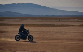 Stock Video Motorcyclist Crossing A Desert Surrounded By Mountains