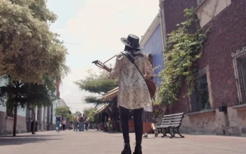 Stock Video Mujer Caminando Por Una Calle Colonial Mientras Toca Su Guitarra