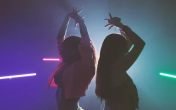 Stock Video Pair Of Girls Dancing Back To Back Under Colored Lights