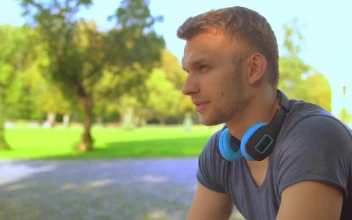 Stock Video Pensive Young Man Listening To Music On His Headphones