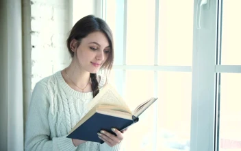 Stock Footage Woman Reading Book Near Bright Window Free