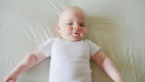 Stock Video Happy Baby Lying On White Bed In White Shirt Animated Wallpaper - Free Live Wallpaper