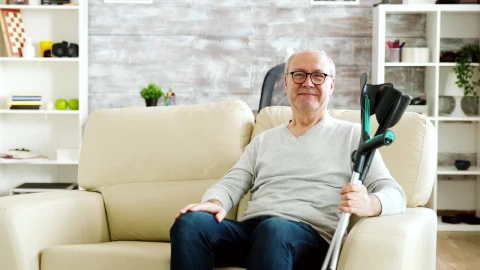 Free Video Stock Smiling Elderly Man Holding Crutches And Sitting On Sofa Live Wallpaper - Free Live Wallpaper