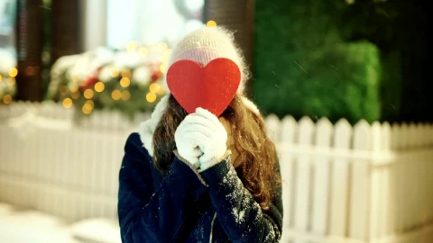 Free Video Stock Smiling Woman Covers Face With Heart Cutout In Snowy Street Live Wallpaper - Free Live Wallpaper