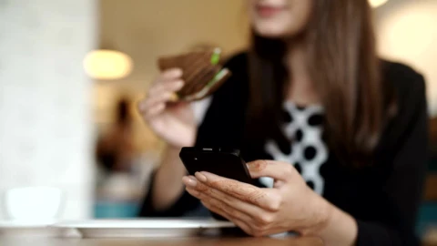 Stock Footage Young Woman Eats Sandwich In Cafe While Texting Live Wallpaper Free - Free Live Wallpaper